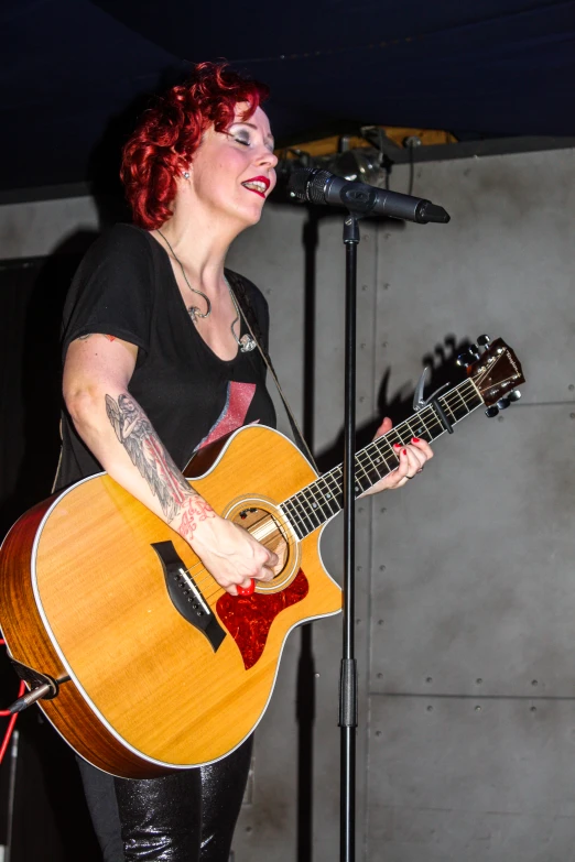 a woman holding a guitar and singing into a microphone