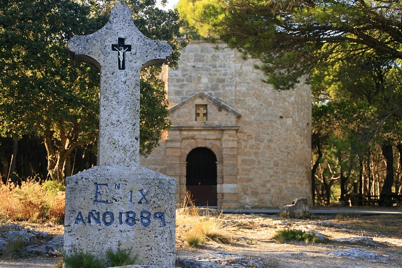 a cross sitting in front of a building and trees