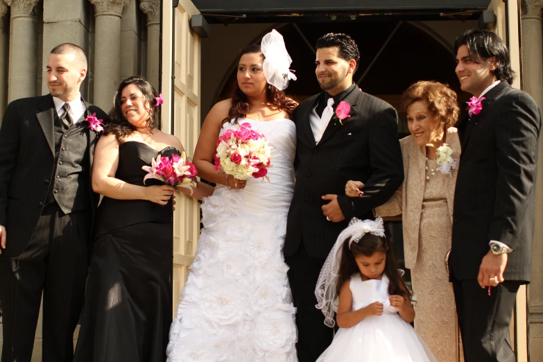 a wedding party in formal wear is standing outside the building