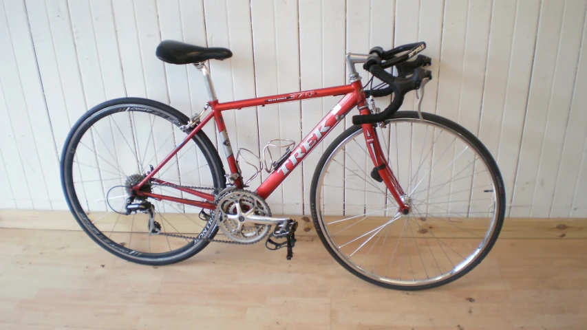 a red bike is hanging against a white wall