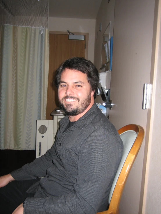 a man in gray shirt sitting at a desk