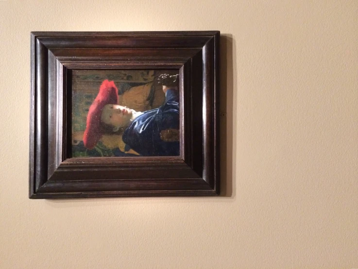 a painting hangs in a framed wooden frame on the wall