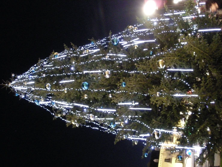 the top of a very tall christmas tree that has decorations and lights all over it