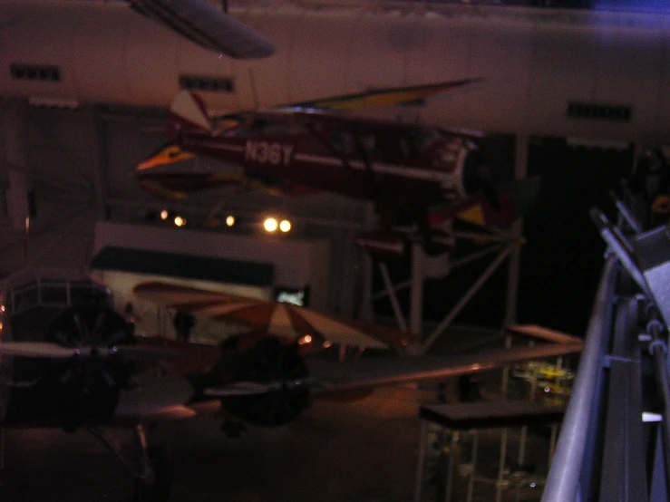 two airplanes in a hangar and two men stand on the stairs