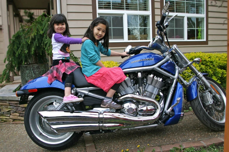 two s sitting on a blue motorcycle