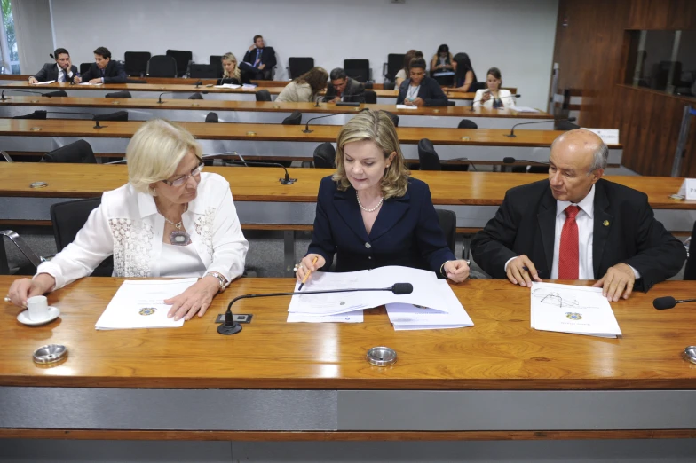 three people sitting at the tables in a conference room