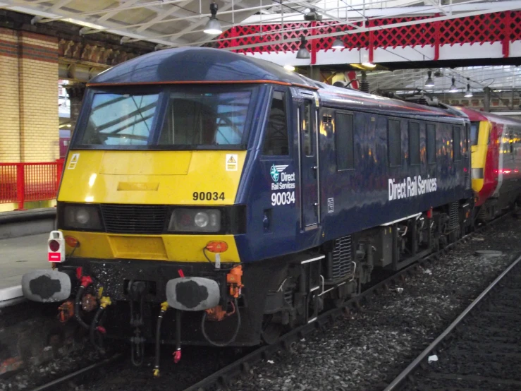 a blue train pulling into a station next to its platform