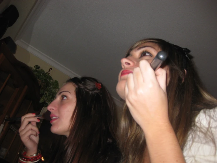 two girls are brushing their teeth with the same brush