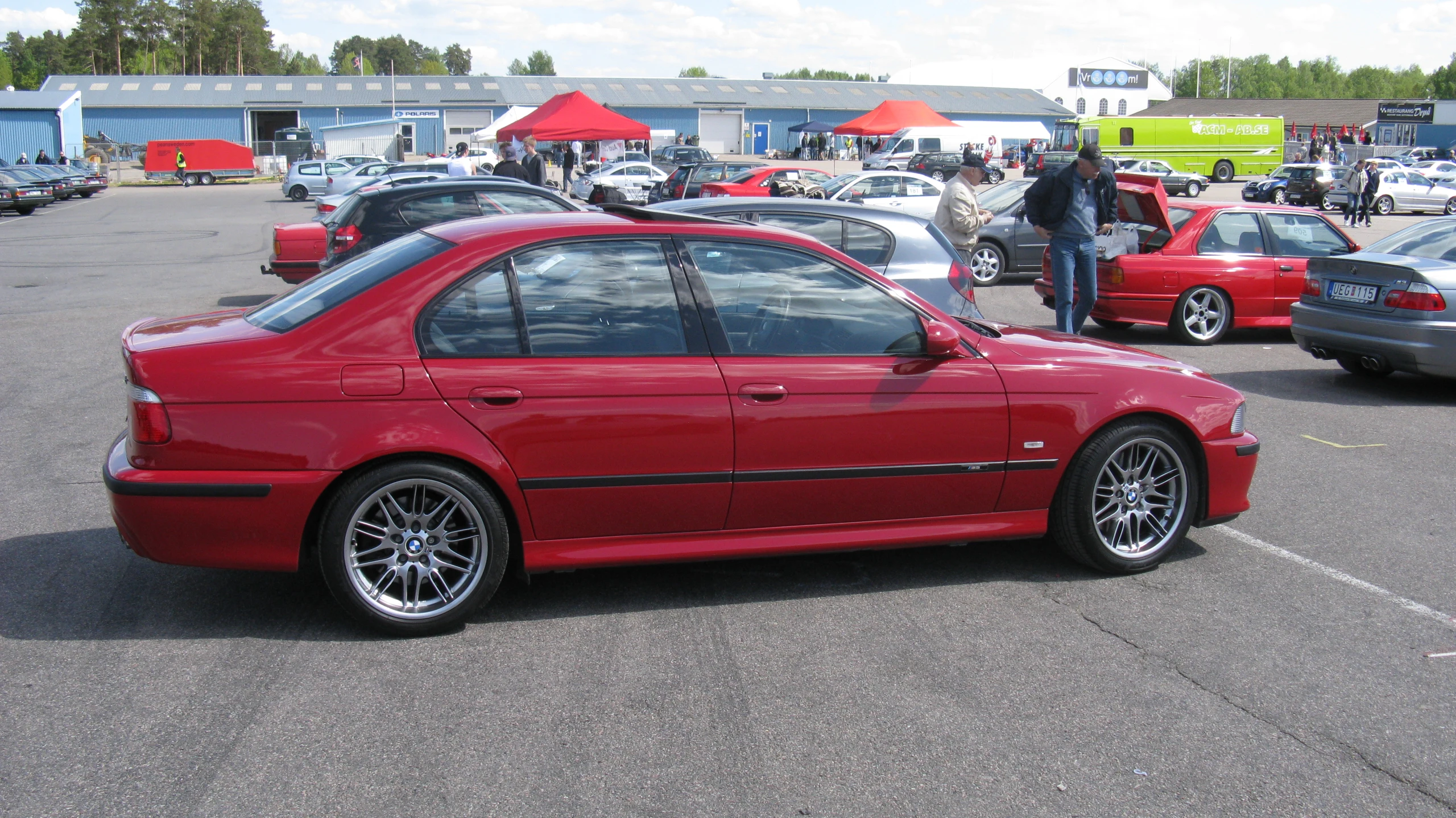 the rear end of a red car sitting in a parking lot