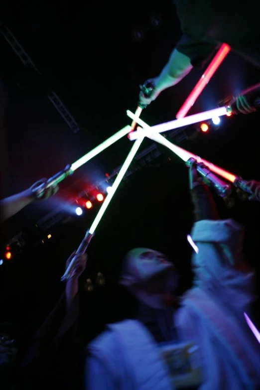 people standing under lights with sticks in the air