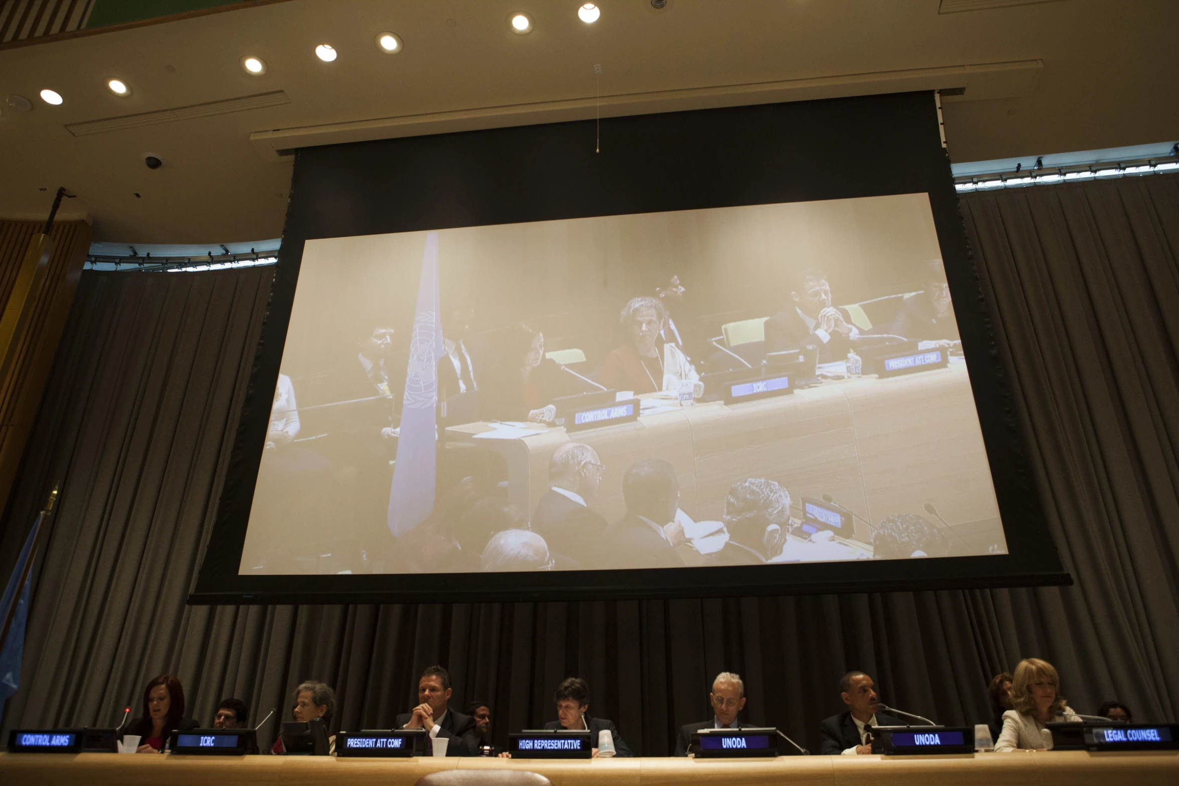 people at tables with laptops and projection screen in background