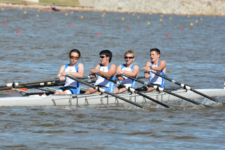 four men are rowing on the water in a boat