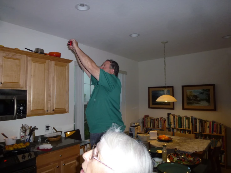 a man stands on his kitchen island and reaches in to the air