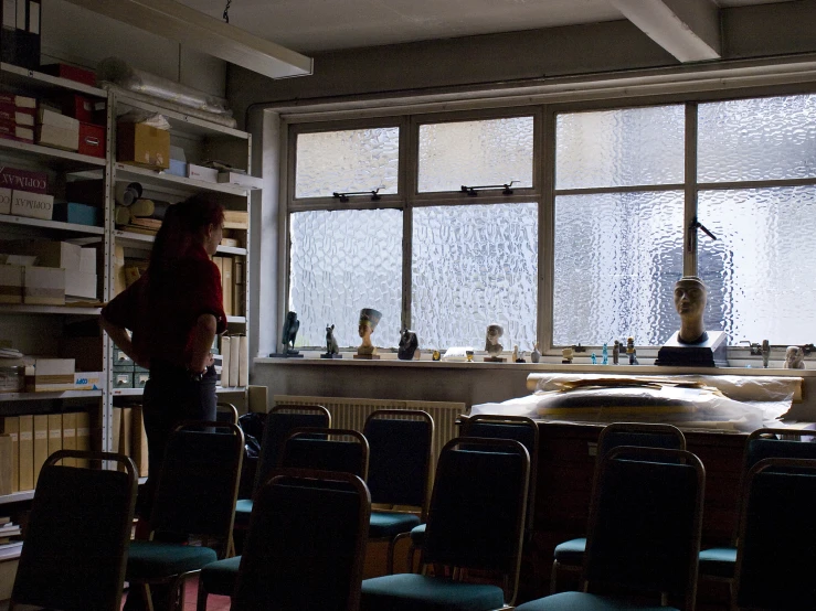 a woman standing next to a chair near windows