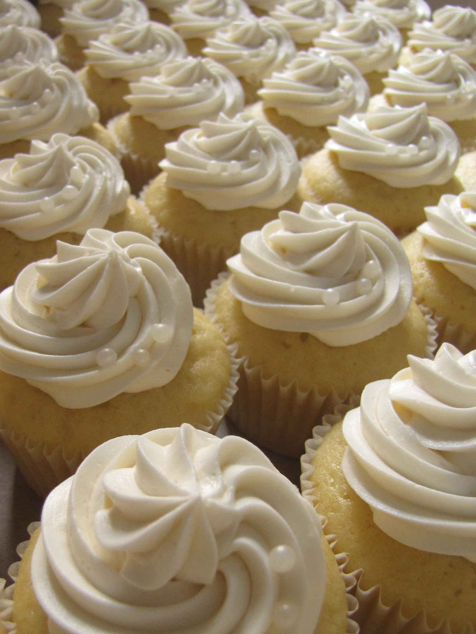 many cupcakes with white frosting on top of them