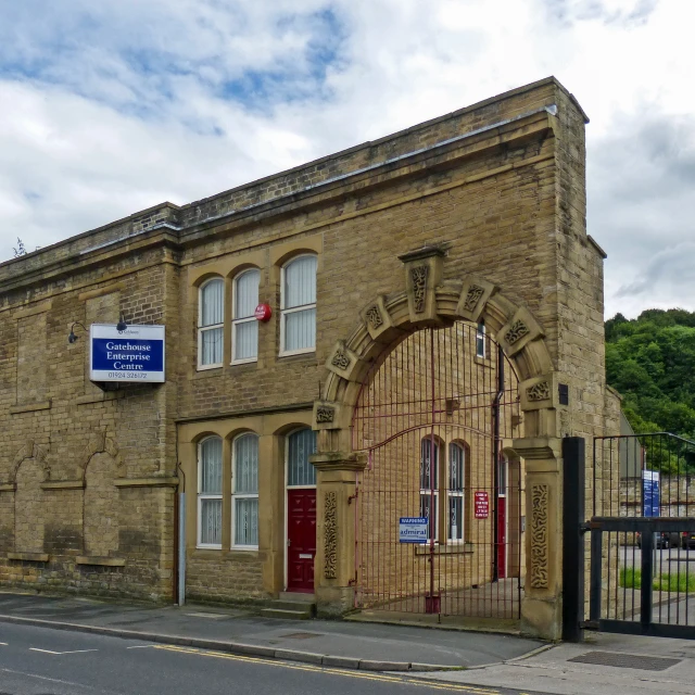 a brown brick building with a red door and fence