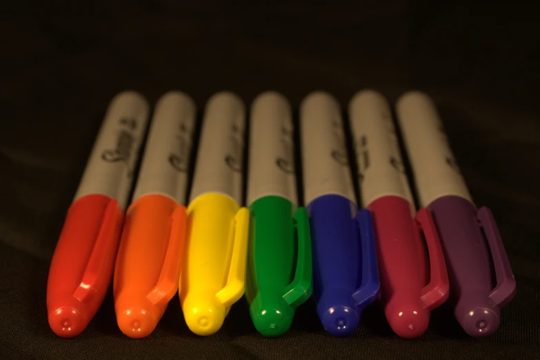 nine pens are lined up with one rainbow in the middle