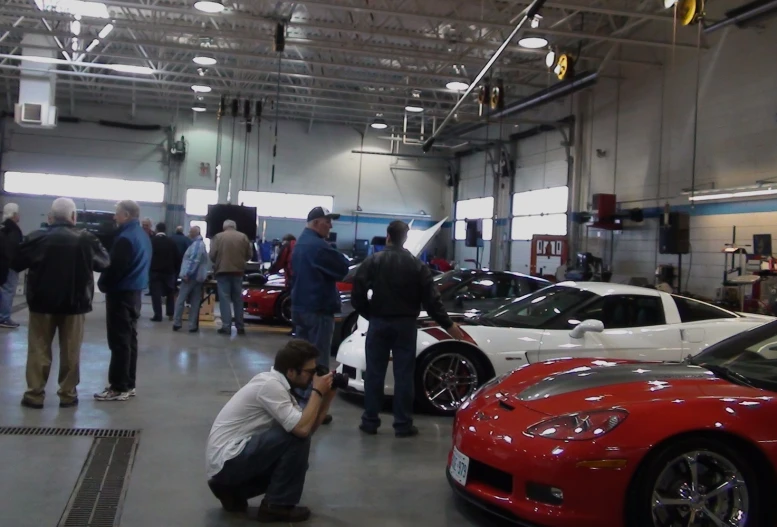 a group of people stand inside a show room in front of their cars