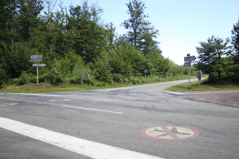 a road with one lane with signs and a crosswalk and two street lights