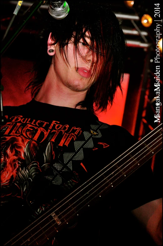 a guy playing a guitar and a microphone in a dark room