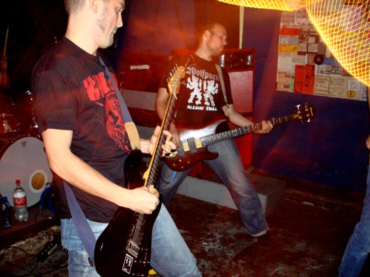 two men in black shirts and jeans are playing guitars