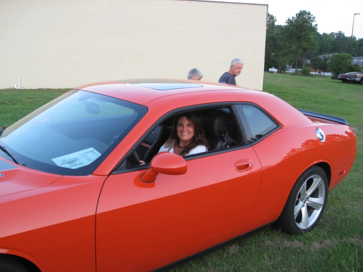 a smiling woman driving a car on the grass