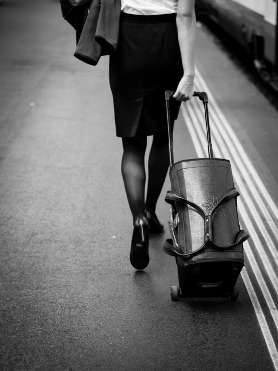 a woman carrying luggage down a track