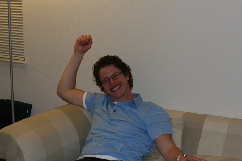 a young man wearing glasses is sitting on a couch