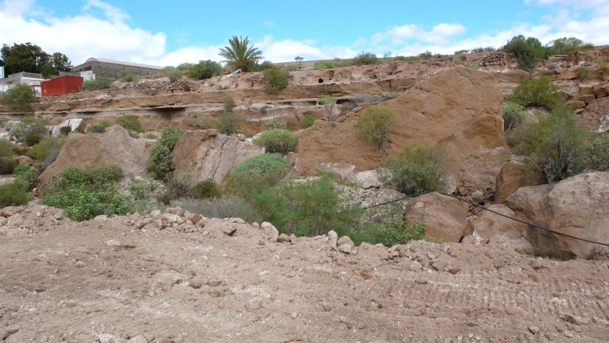 a rocky hill next to a house with a wire fence