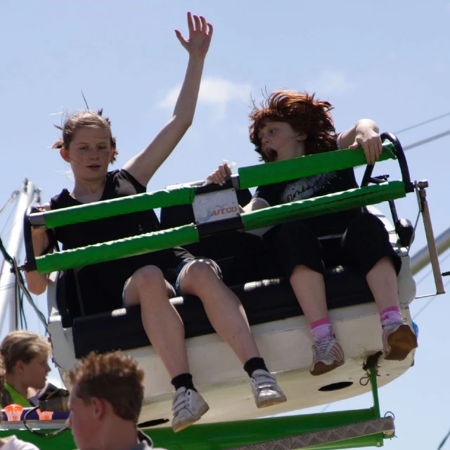 three girls sit in the ferris wheel waving to a crowd