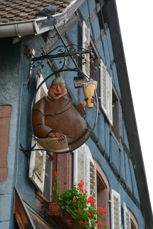 an iron sculpture of a fish is mounted to a blue building