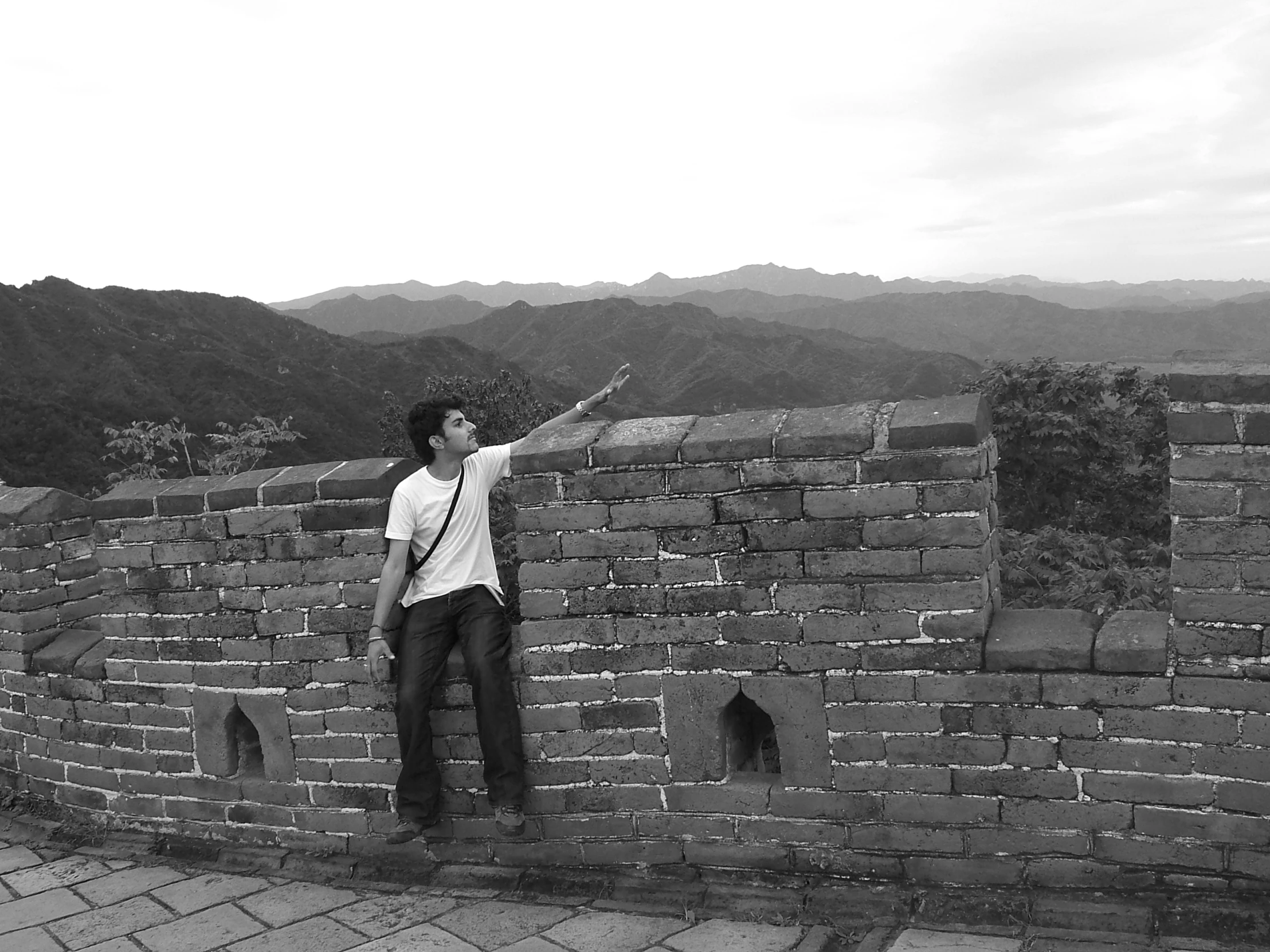 man on the top of an ancient brick wall pointing to the side