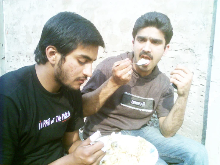 two men eating soing out of a bowl