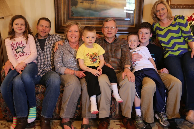 a family sitting on a couch smiling for the camera