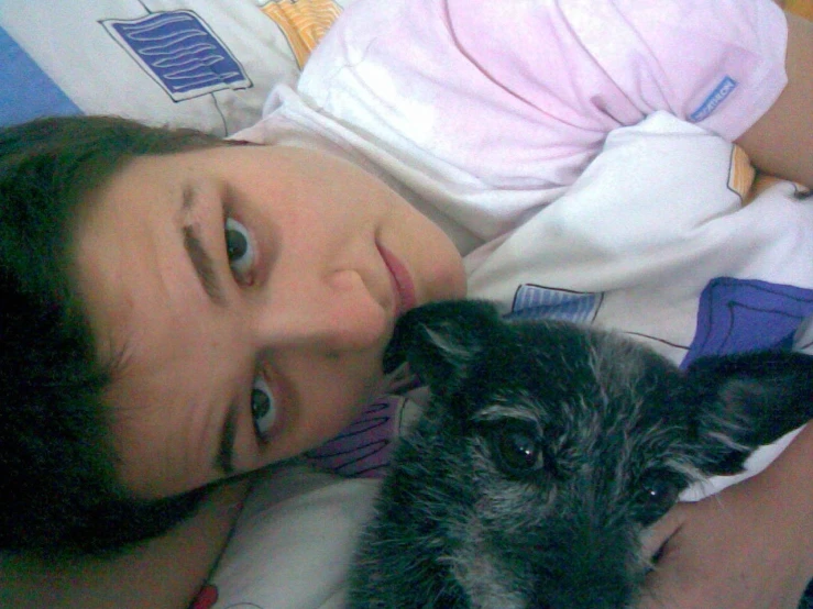 a boy holding a dog while laying in bed