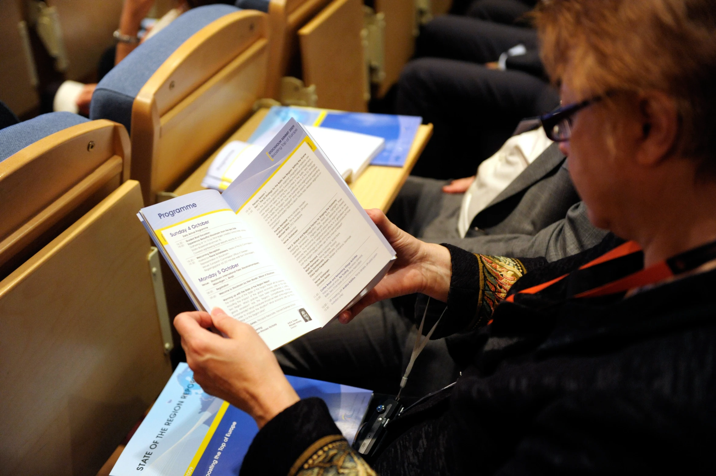 a person sitting in front of a lecture room holding up an open book