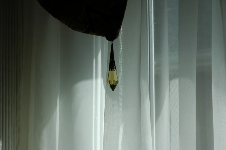 a clock hanging from the curtain of a window