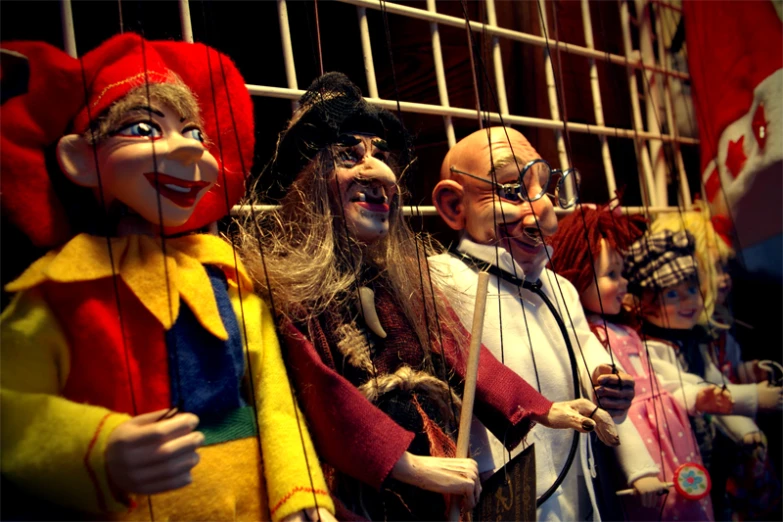 several clowns with long hair and full face make up standing in front of a cage