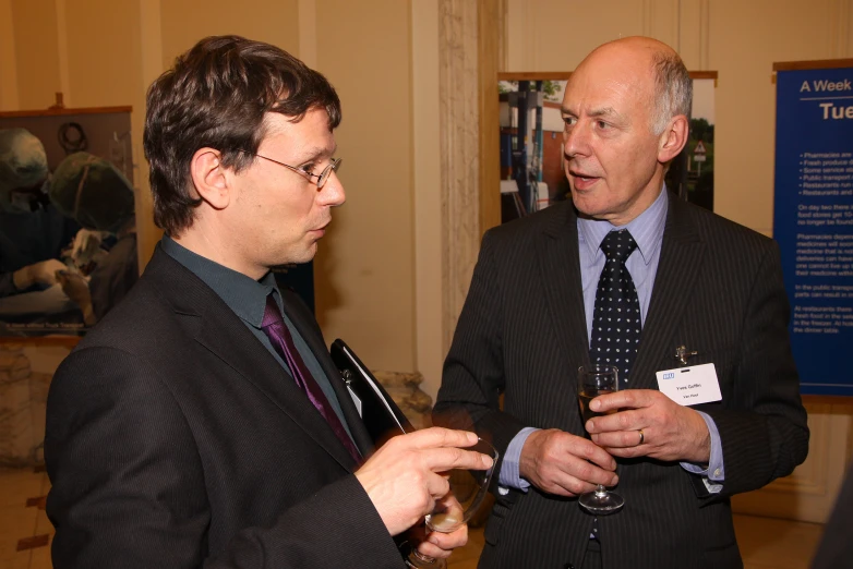 two men talk at an event in the middle of the room