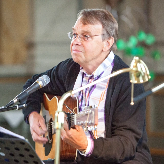 a man is playing a guitar at the microphone