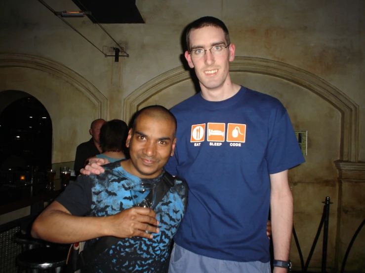 two men standing in a dimly lit room with one being hugged by the other