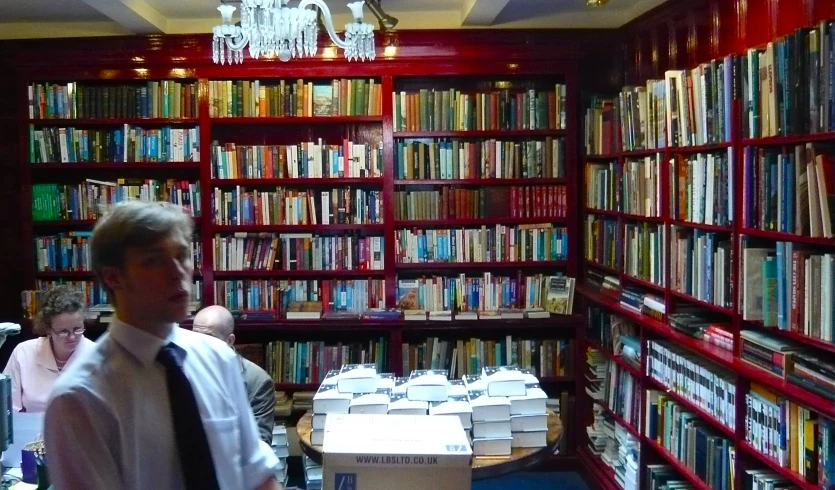 man wearing a tie in the middle of a room full of books