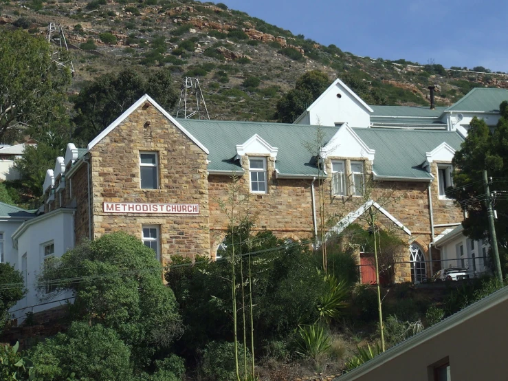 a brick building in front of some trees and a hill