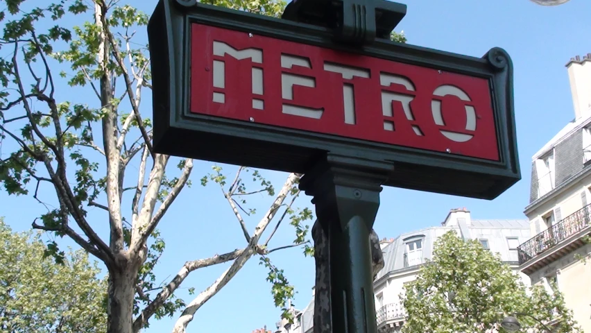 a metro sign on a post in front of some buildings