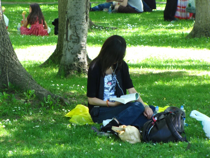 a young lady sitting on the grass with some bags