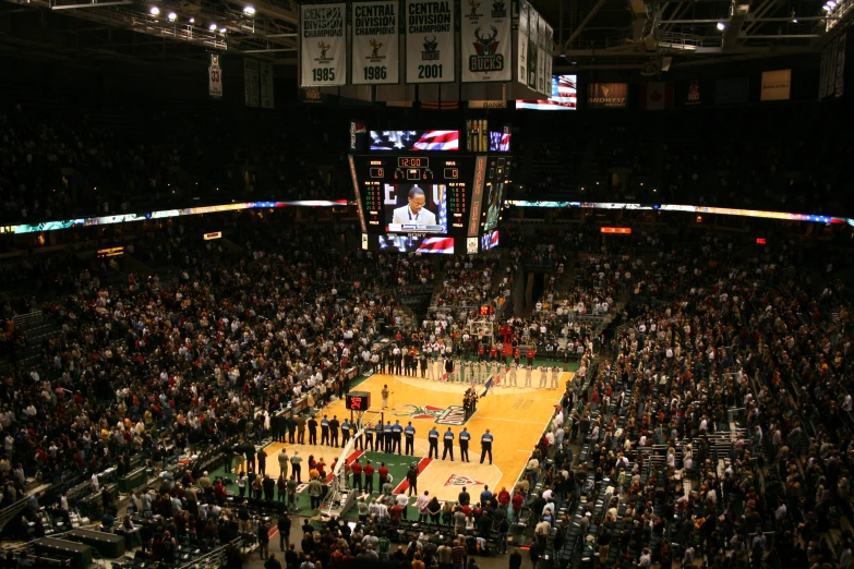an arena filled with people standing and watching a basketball game