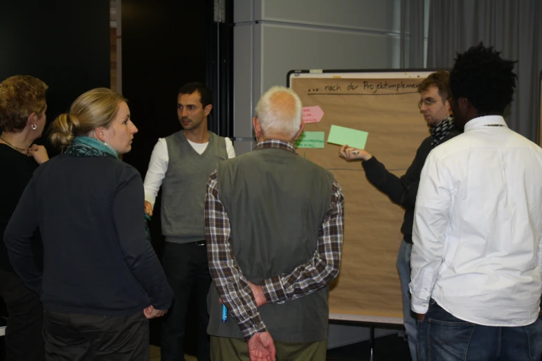 a group of people standing around a brown bulletin board