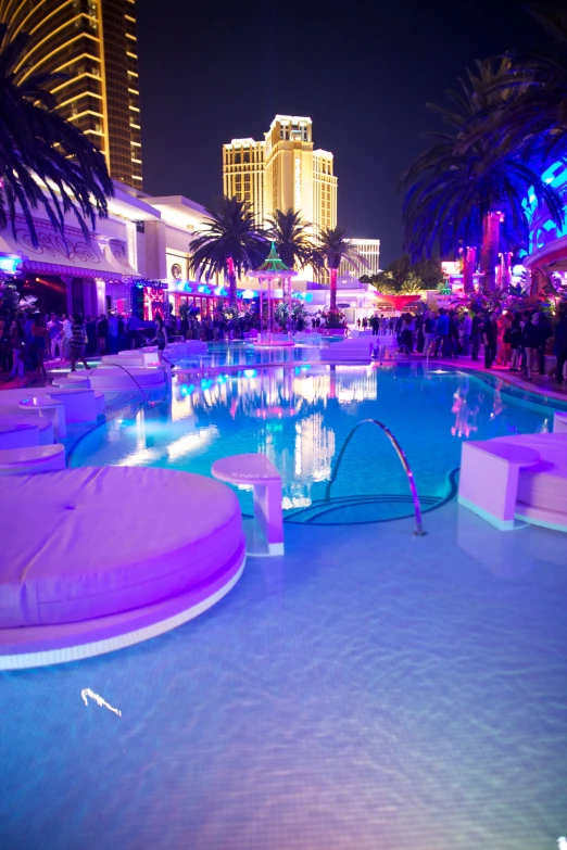 an empty swimming pool with illuminated buildings in the background