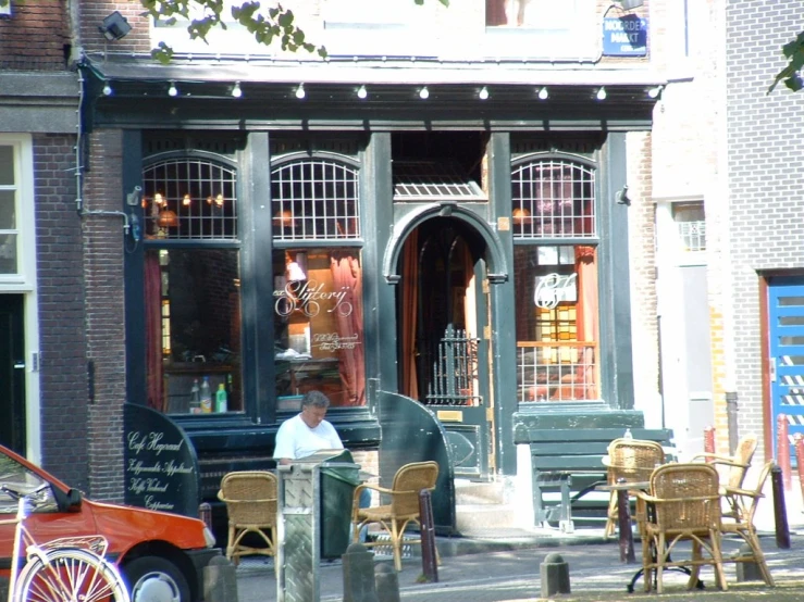 a man sitting at an outdoor cafe talking on a phone