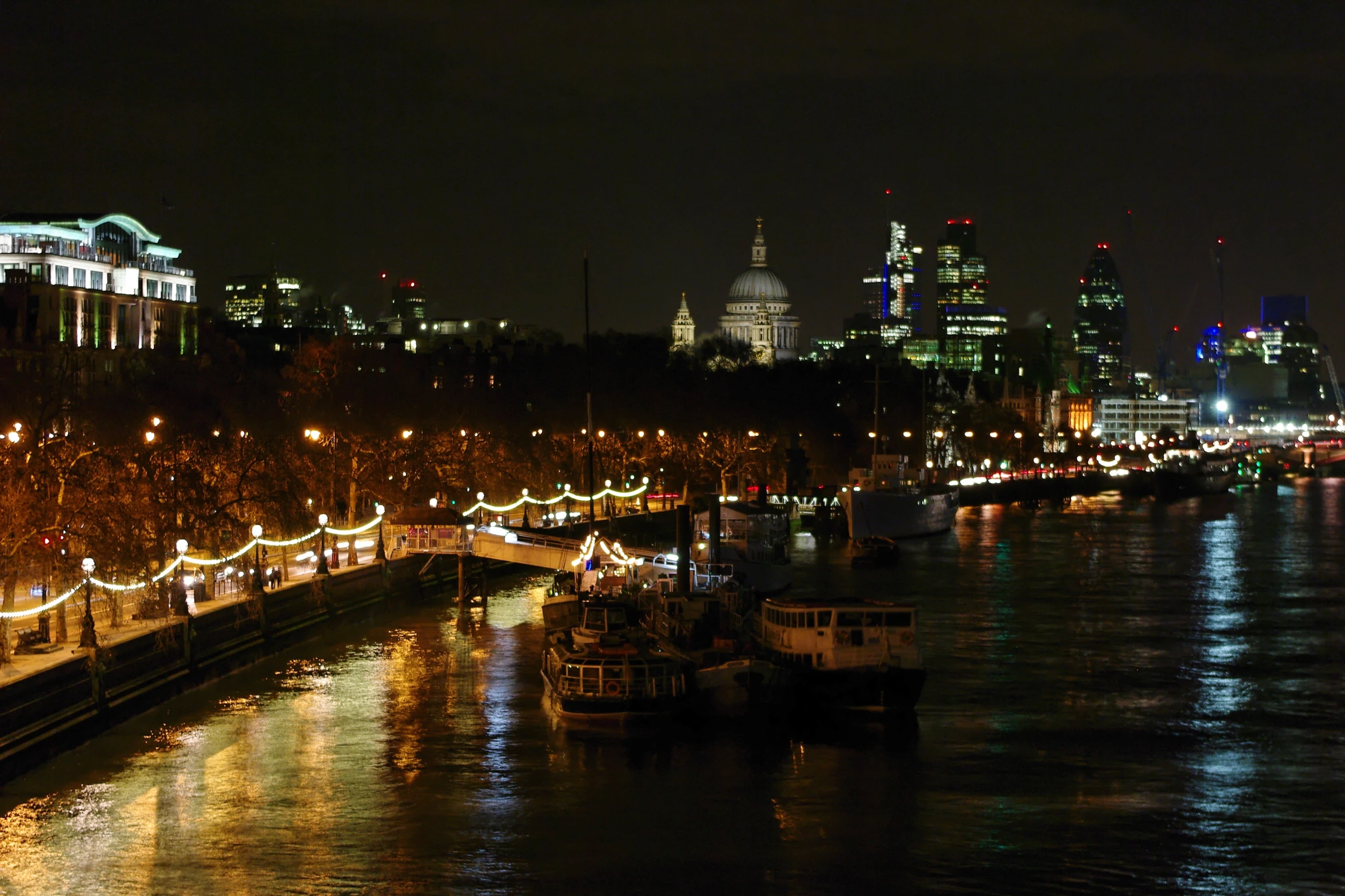 the boats are sailing on the water near city lights